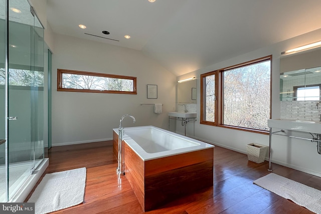 bathroom with vanity, hardwood / wood-style floors, vaulted ceiling, tasteful backsplash, and plus walk in shower