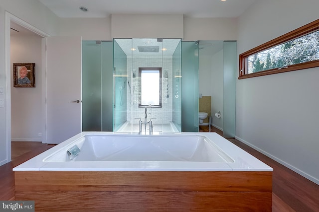 bathroom featuring wood-type flooring, independent shower and bath, a healthy amount of sunlight, and toilet