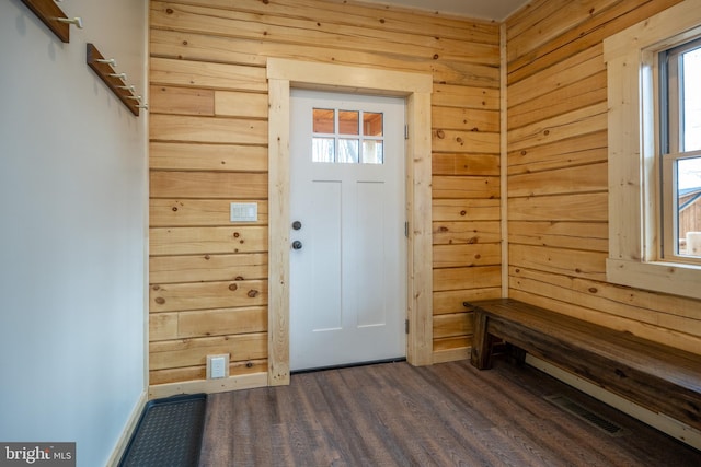 foyer entrance with dark wood-type flooring and wooden walls