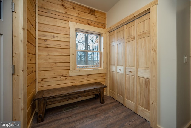 mudroom with dark wood-type flooring and wooden walls