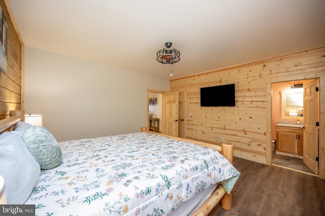 bedroom with wooden walls, dark hardwood / wood-style flooring, and ensuite bath