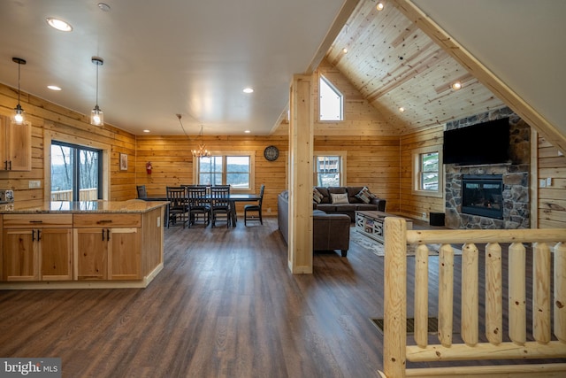 kitchen featuring vaulted ceiling, dark hardwood / wood-style flooring, light stone counters, hanging light fixtures, and wood walls