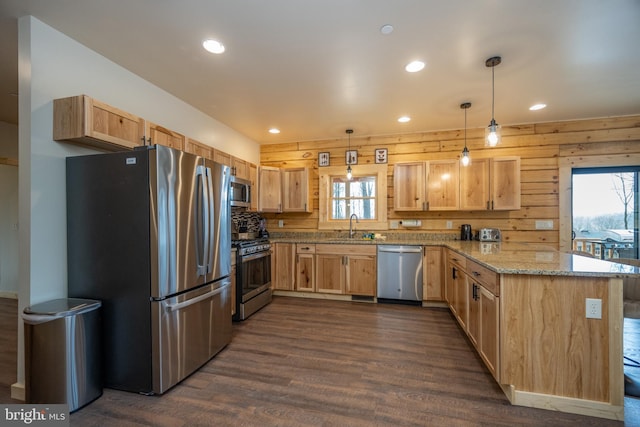 kitchen featuring stainless steel appliances, decorative light fixtures, wooden walls, and kitchen peninsula