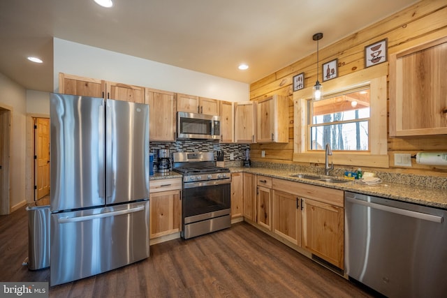 kitchen featuring light stone countertops, dark hardwood / wood-style flooring, appliances with stainless steel finishes, decorative light fixtures, and sink