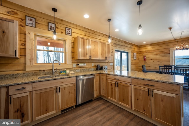 kitchen with decorative light fixtures, sink, wood walls, and stainless steel dishwasher