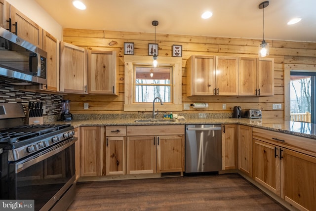 kitchen featuring decorative light fixtures, dark hardwood / wood-style floors, stainless steel appliances, sink, and wooden walls