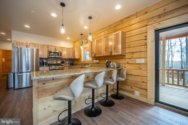 kitchen with dark hardwood / wood-style floors, wooden walls, backsplash, and appliances with stainless steel finishes