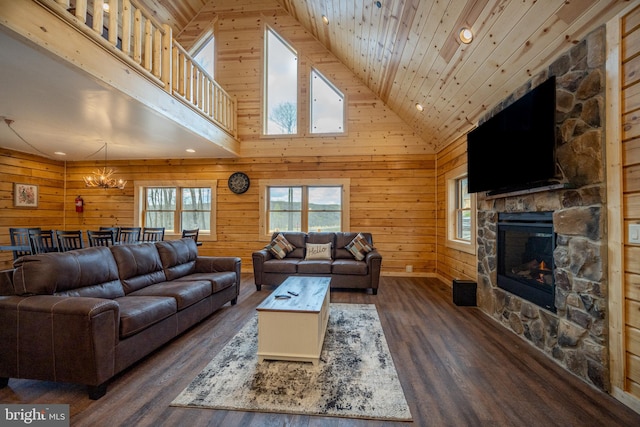 living room featuring dark hardwood / wood-style floors, a fireplace, a notable chandelier, high vaulted ceiling, and wooden walls