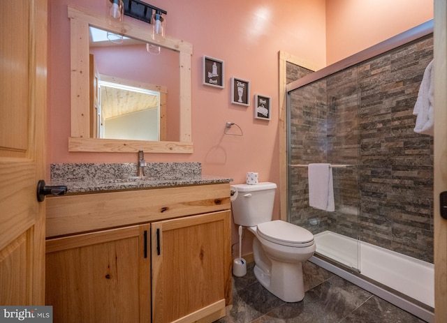 bathroom featuring a shower with door, tile flooring, toilet, and vanity with extensive cabinet space