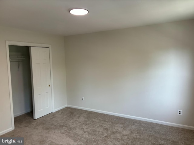 unfurnished bedroom with a closet and light colored carpet