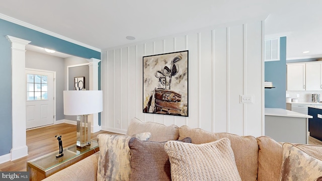 living room with ornamental molding, light hardwood / wood-style flooring, and decorative columns