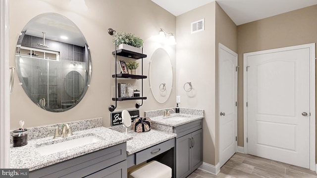 bathroom with a shower with shower door, tile floors, and dual vanity