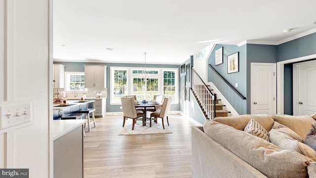 living room featuring crown molding, an inviting chandelier, and light wood-type flooring