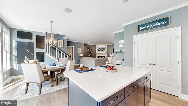 kitchen featuring a center island, ornamental molding, light hardwood / wood-style floors, and decorative light fixtures