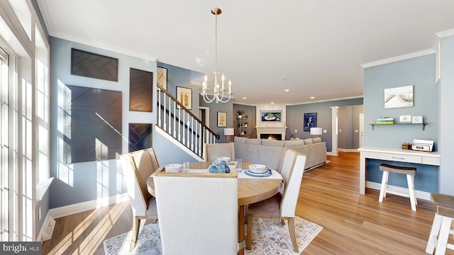 dining space featuring light hardwood / wood-style flooring, crown molding, ornate columns, and a chandelier