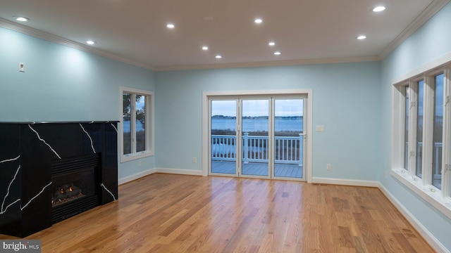 1707 Bay St, Fenwick Island, DE 19944 - unfurnished living room with crown molding, light wood-style flooring, baseboards, and a warm lit fireplace
