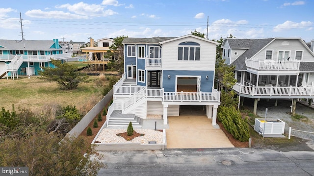 1707 Bay St, Fenwick Island, DE 19944 - raised beach house featuring a carport, concrete driveway, a residential view, and stairs