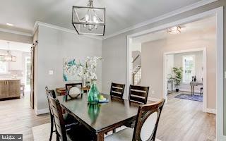 dining room with hardwood / wood-style floors, crown molding, and a notable chandelier