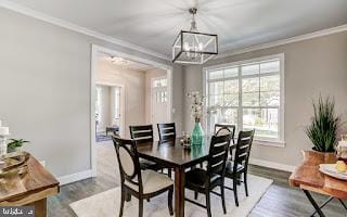 dining space featuring a chandelier, wood-type flooring, and ornamental molding