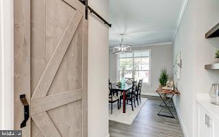 interior space with a barn door, crown molding, and dark wood-type flooring