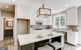 kitchen featuring white cabinets, decorative light fixtures, a kitchen island, and light wood-type flooring