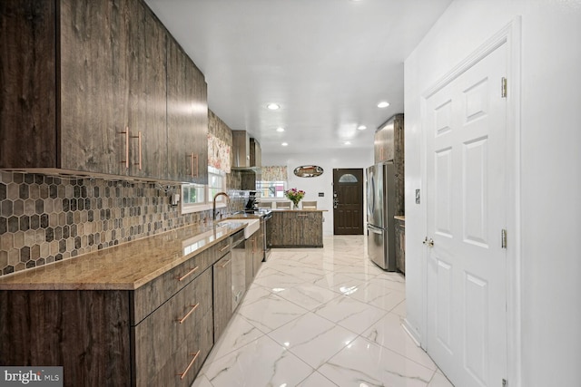 kitchen featuring dark brown cabinets, tasteful backsplash, light tile flooring, and stainless steel refrigerator