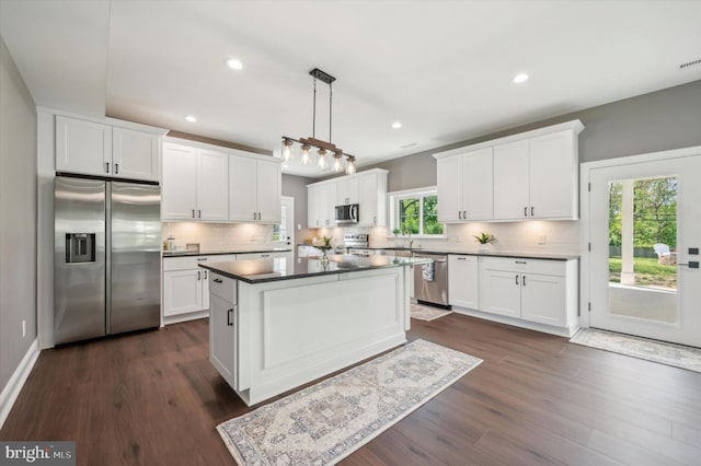 kitchen with appliances with stainless steel finishes, a healthy amount of sunlight, and dark hardwood / wood-style flooring