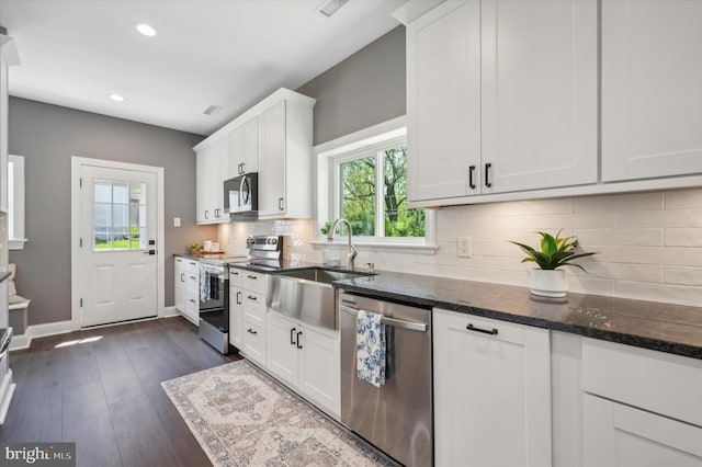 kitchen with white cabinetry, dark wood-type flooring, backsplash, and stainless steel appliances