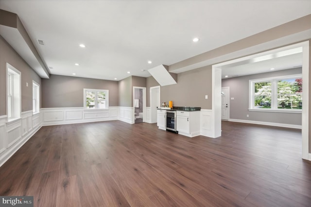 unfurnished living room featuring beverage cooler and dark hardwood / wood-style flooring