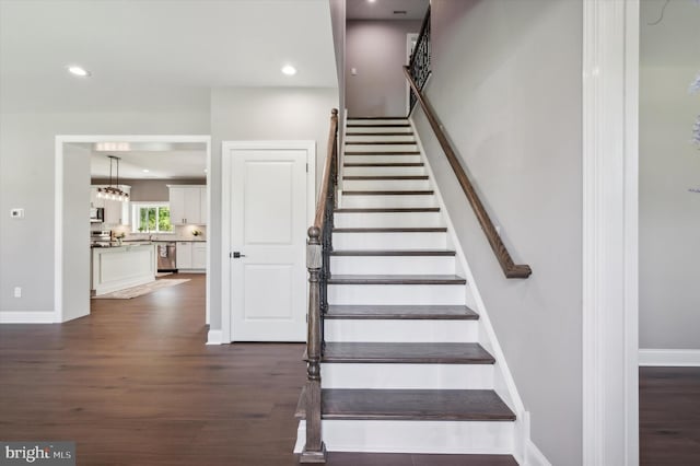 staircase with dark hardwood / wood-style flooring and a chandelier