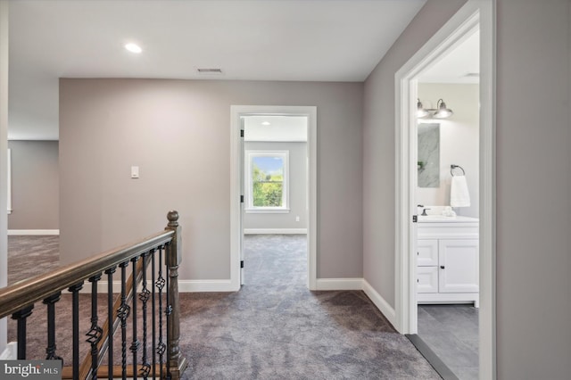 corridor with sink and dark colored carpet