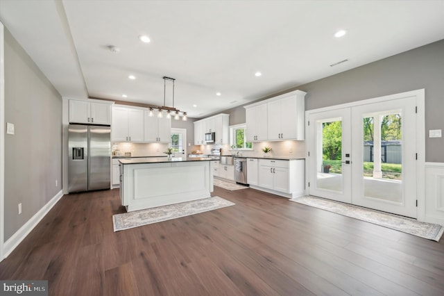 kitchen with dark hardwood / wood-style flooring, stainless steel appliances, tasteful backsplash, white cabinets, and pendant lighting