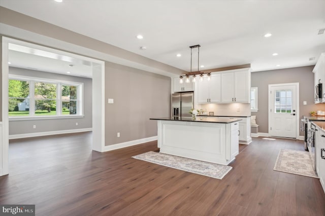 kitchen featuring hanging light fixtures, a kitchen island, appliances with stainless steel finishes, dark hardwood / wood-style floors, and backsplash