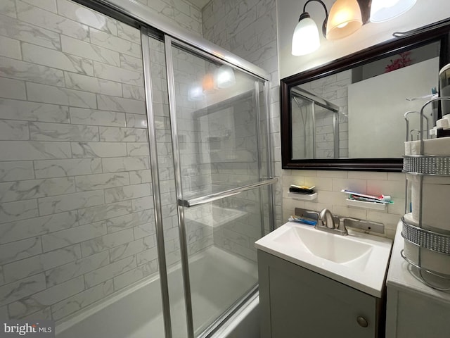 bathroom featuring tile walls, tasteful backsplash, vanity with extensive cabinet space, and enclosed tub / shower combo