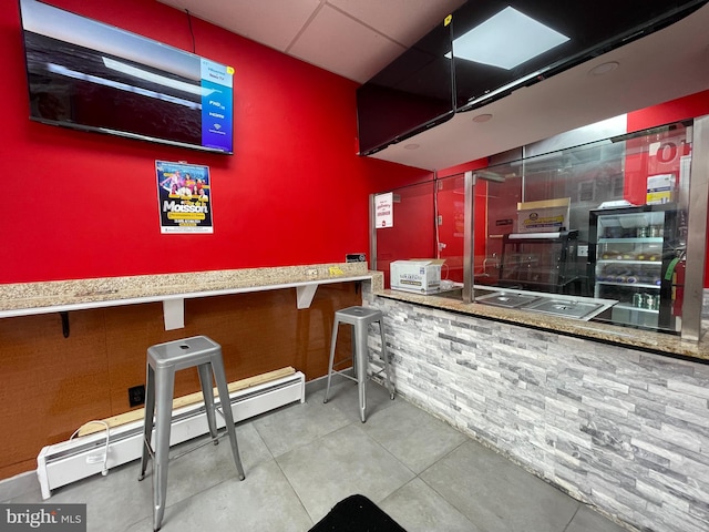 bar with a baseboard radiator and light tile floors