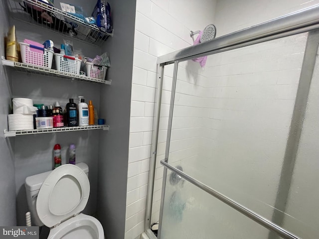 bathroom with a shower with shower door and toilet