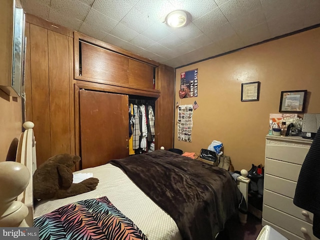 bedroom with a closet and wooden walls