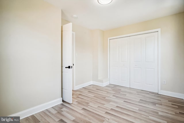 unfurnished bedroom with a closet and light hardwood / wood-style floors