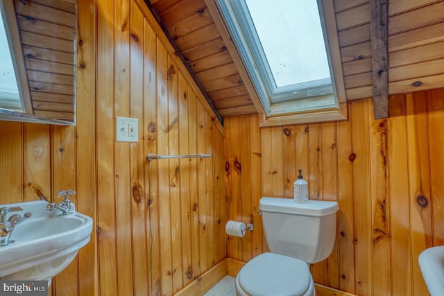 bathroom with toilet, wood walls, a skylight, a sink, and wood ceiling