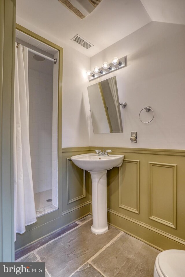 full bath with visible vents, toilet, a wainscoted wall, a shower stall, and a decorative wall