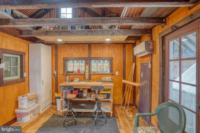 dining space featuring a wall unit AC, wood walls, and light wood-style floors