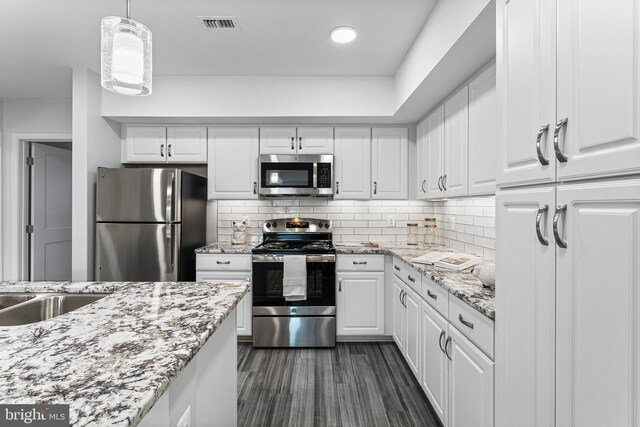 kitchen featuring backsplash, pendant lighting, stainless steel appliances, and white cabinets