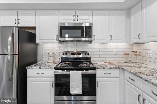 kitchen featuring tasteful backsplash, stainless steel appliances, white cabinets, and light stone countertops