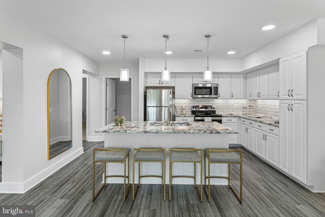 kitchen featuring light stone counters, backsplash, white cabinetry, hanging light fixtures, and stainless steel appliances