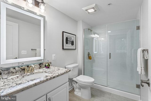 bathroom with a shower with door, tile floors, vanity, and toilet