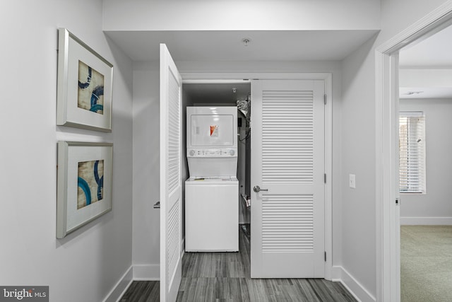 laundry area featuring dark carpet and stacked washer and dryer