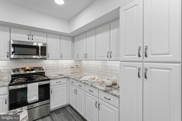 kitchen with appliances with stainless steel finishes, backsplash, white cabinetry, and light stone countertops