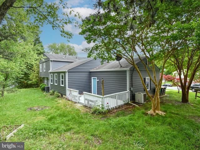 rear view of property featuring a deck, a yard, and central air condition unit