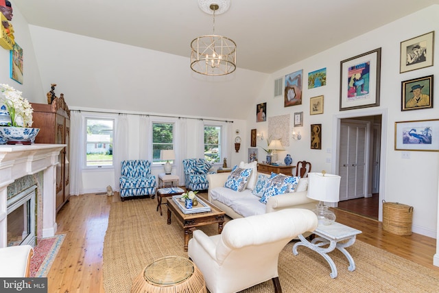 living room with a healthy amount of sunlight, a fireplace, an inviting chandelier, and light wood-type flooring