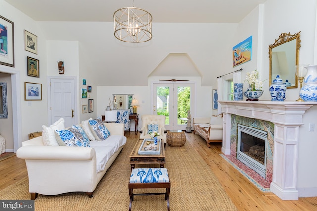 living room featuring an inviting chandelier, light wood-type flooring, and a high end fireplace